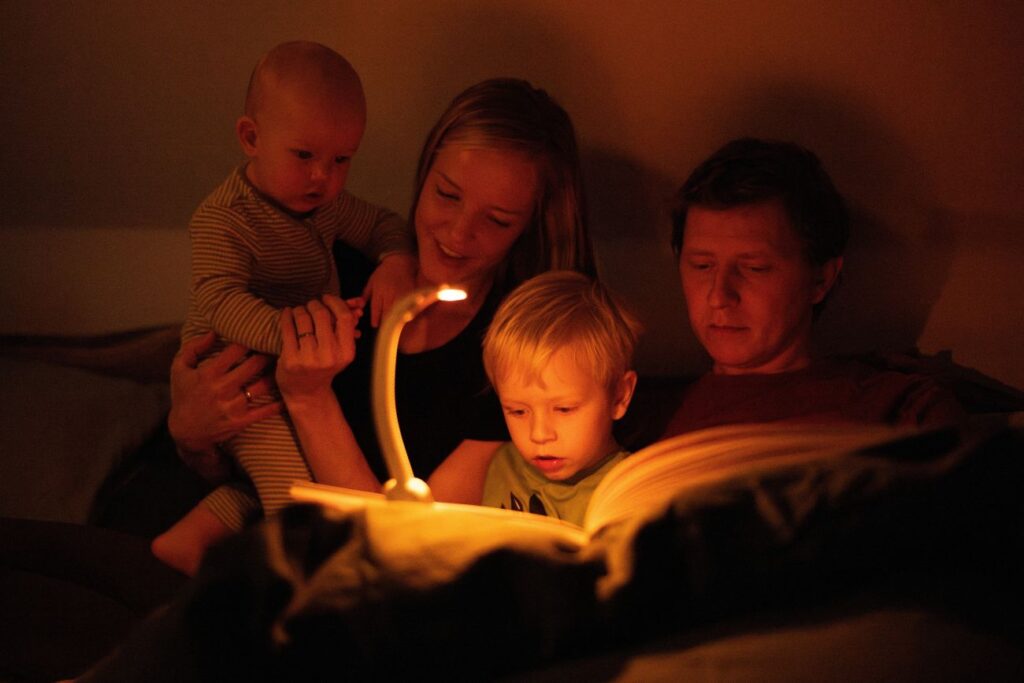 Rodina si čte knížku a svítí si večerní LED lampičkou ORANŽOVKA